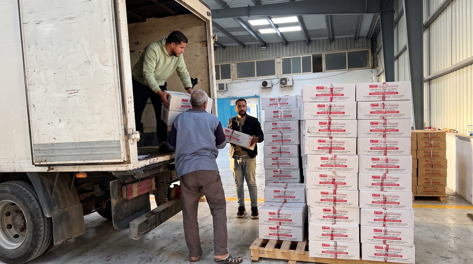 Team loading cartons onto truck inside warehouse
